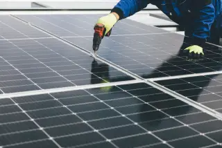 Technicien fixant un panneau photovoltaïque sur une toiture